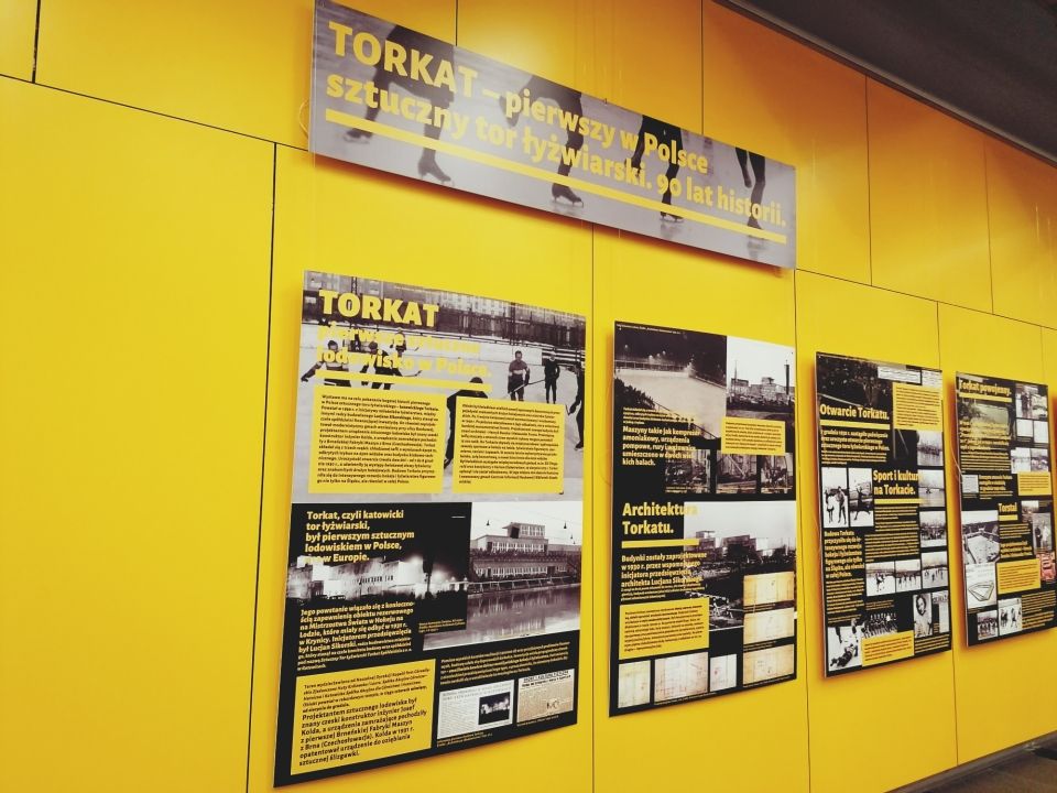 tablice z historią Torkatu na żółtych panelach ściennych