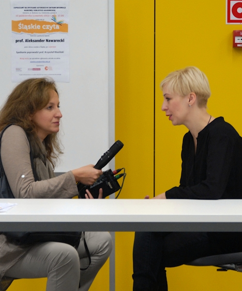 dwie kobiety siedzące przy stole: Magdalena Piekorz udzielająca wywiadu