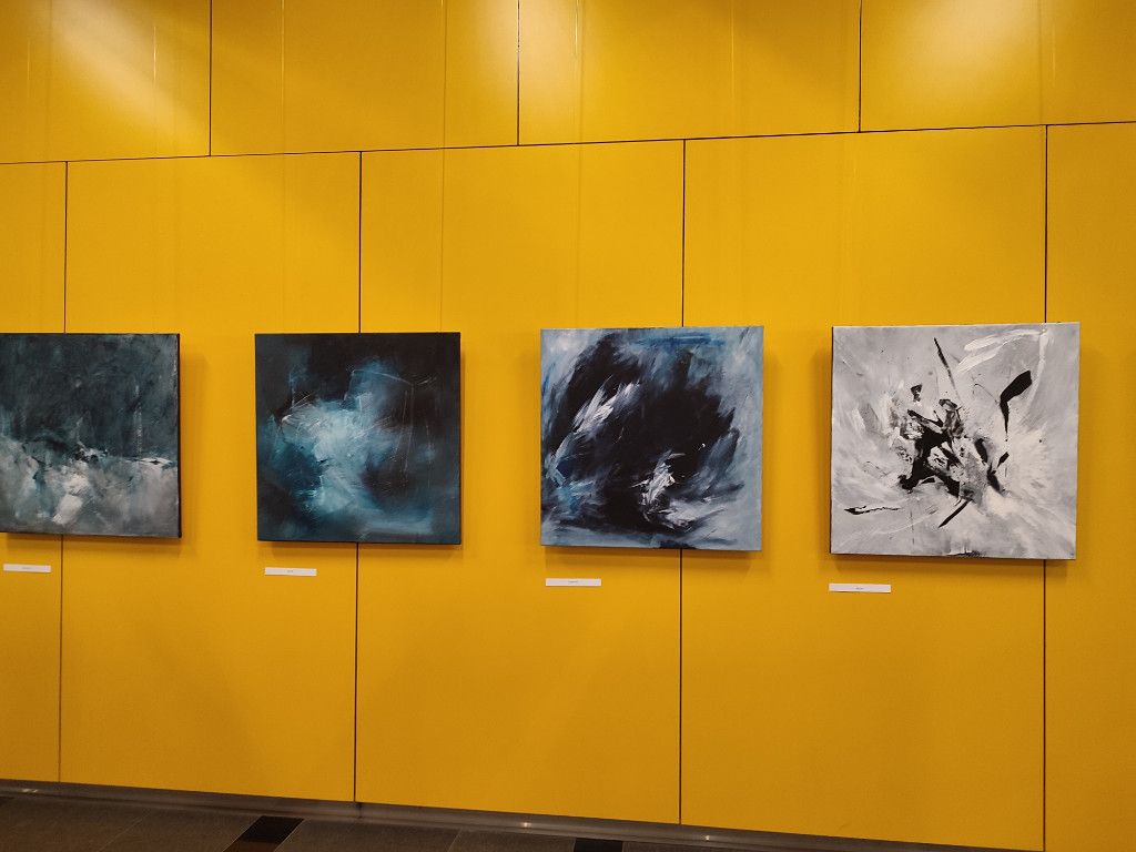 wernisaż wystawy prac Martyny Chojnackiej (wrzesień 2023) zdjęcie kilku prac na żółtej ścianie w holu ciniby