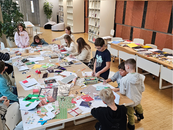 dzieci przy stołach tworzące kartki świąteczne