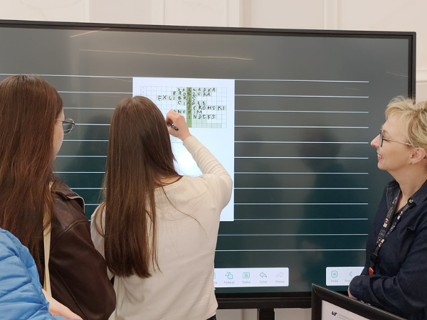 trzy osoby przy interaktywnej tablicy